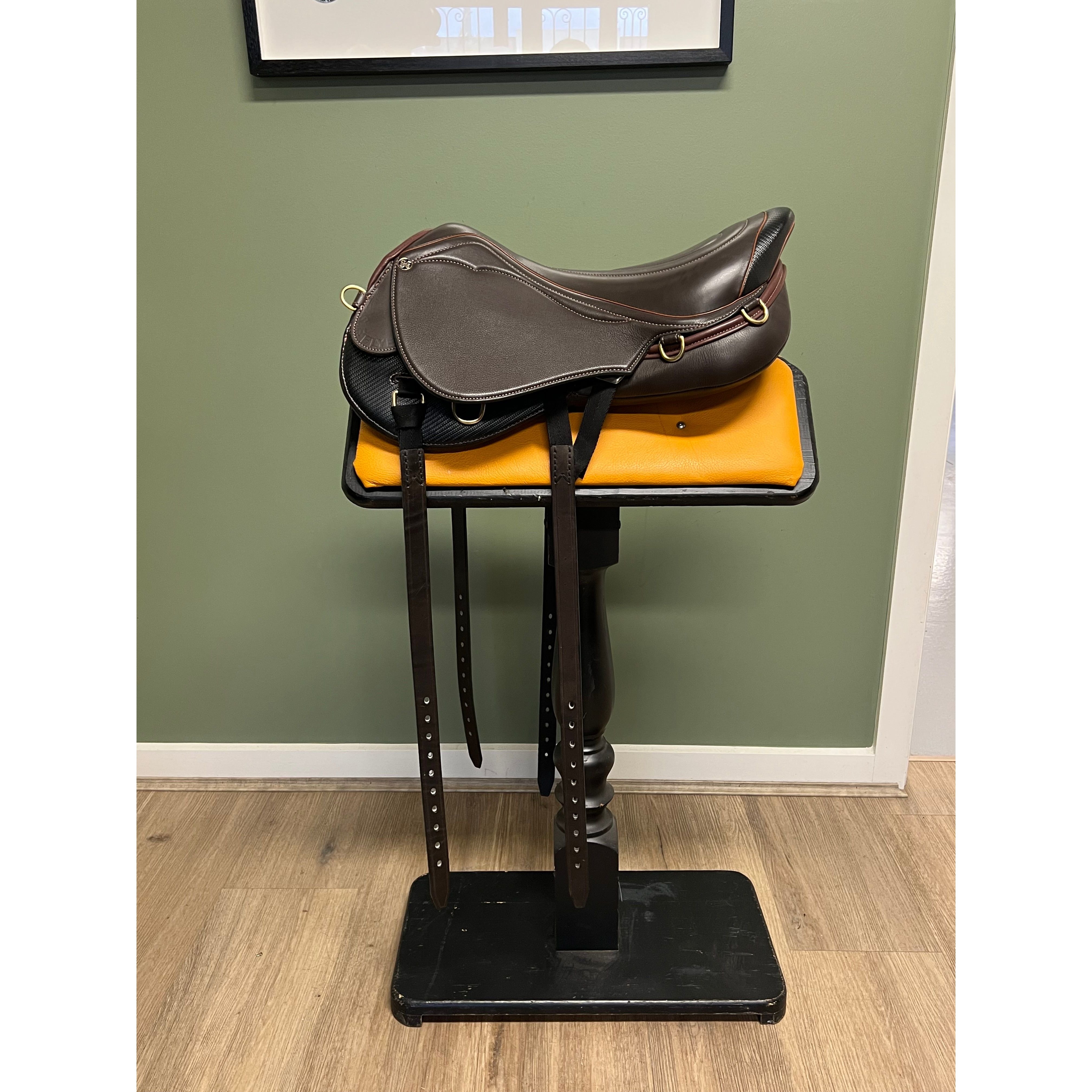 A brown StrideFree endurance flyer saddle displayed on a black saddle stand